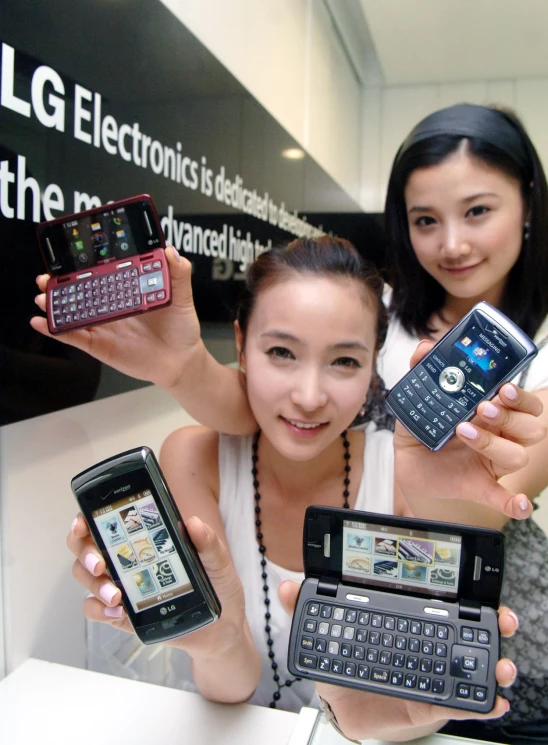 two woman are holding cellphones and looking at one another