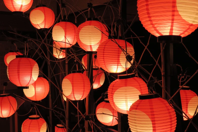 several rows of red paper lanterns hanging from a black metal fence