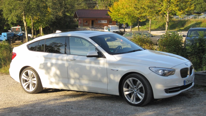 the white car is parked beside a wooded area