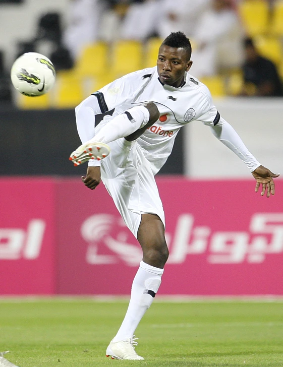 a man kicking a soccer ball on top of a field