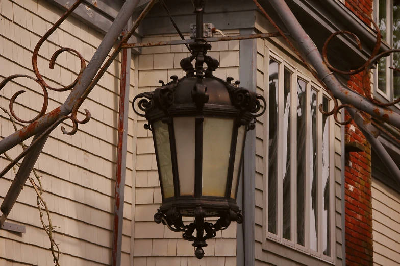 a decorative lamp hanging from a metal pole outside a house