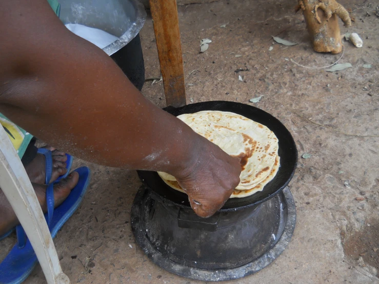 a person in the dirt frying food