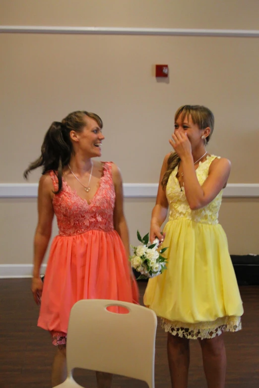 two s in yellow dresses standing around talking