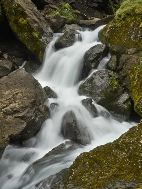 a stream with white water is flowing between rocks