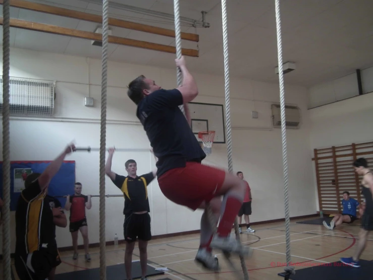 two guys are in a gym jumping over ropes