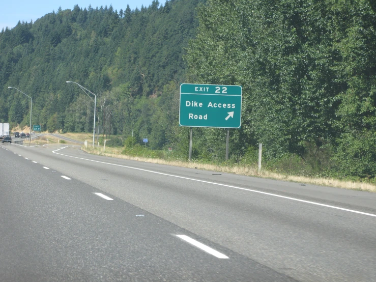 a green highway sign that says elk route near trees