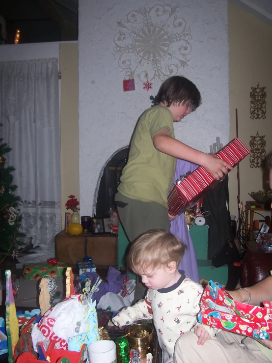 two women standing next to a christmas tree with presents in front of them