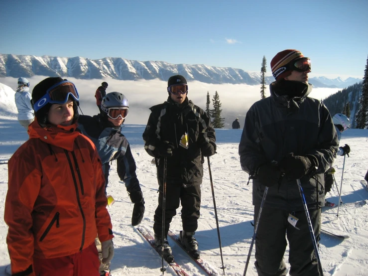 five skiers standing in the snow in front of some mountain top