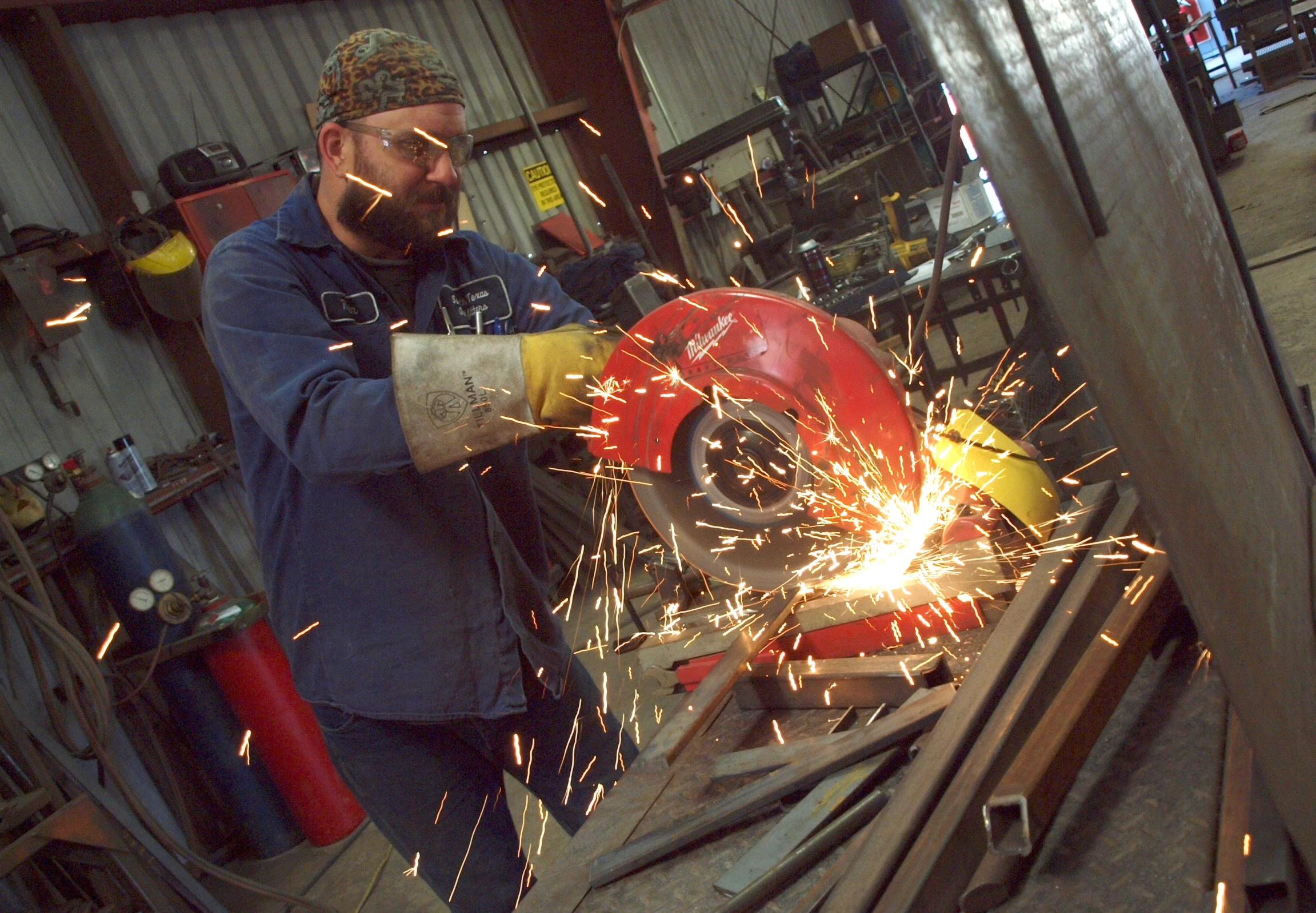 a man in a blue jacket  metal with a circular saw