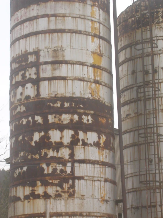 two rusty old tanks are sitting in the grass