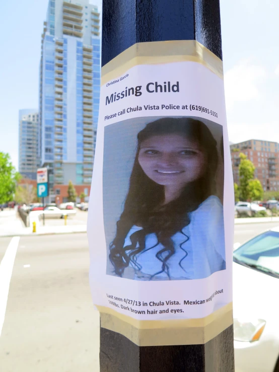 a missing child poster posted to a city street pole