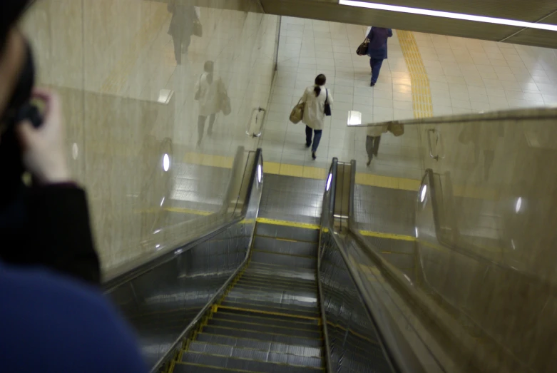a person standing on a phone near an escalator