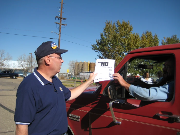 a man holding up a paper next to a truck