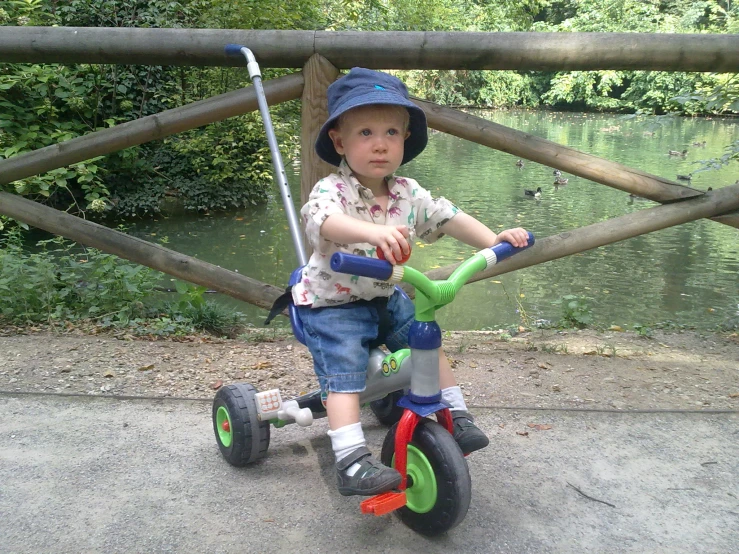 a young child riding a tricycle down a dirt road