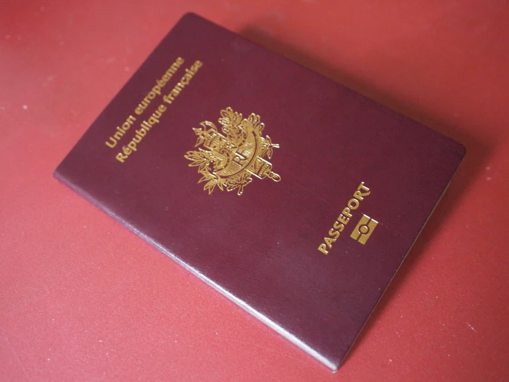 a passport of the philippines lying on top of a red surface
