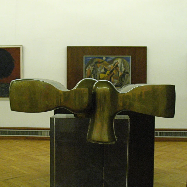 an art exhibit of a large sculpture with artwork in the background