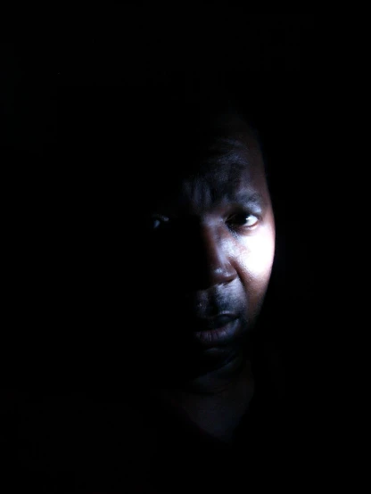 man looking down at his cell phone in the dark