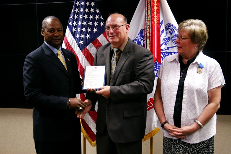 two men and a woman hold an award certificate