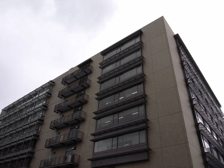 an upward view of an apartment building against a cloudy sky