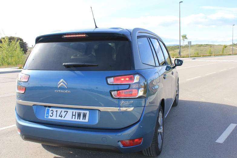 the rear view of a small blue vehicle on the road