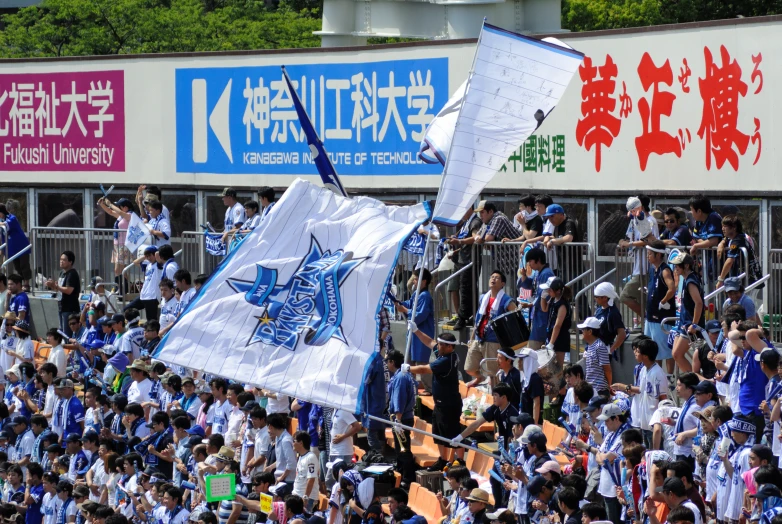 many fans are watching a large event with a white and blue flag