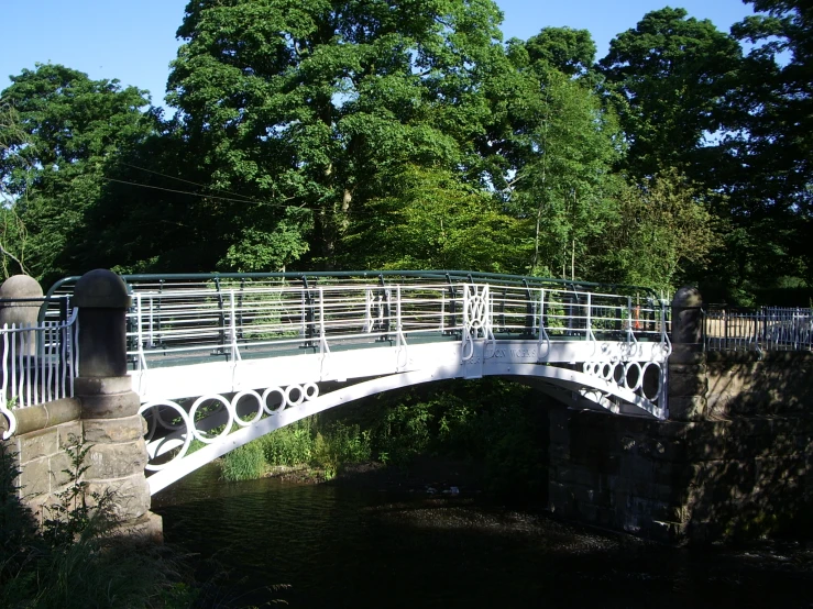 an arched white bridge over water between two bridges
