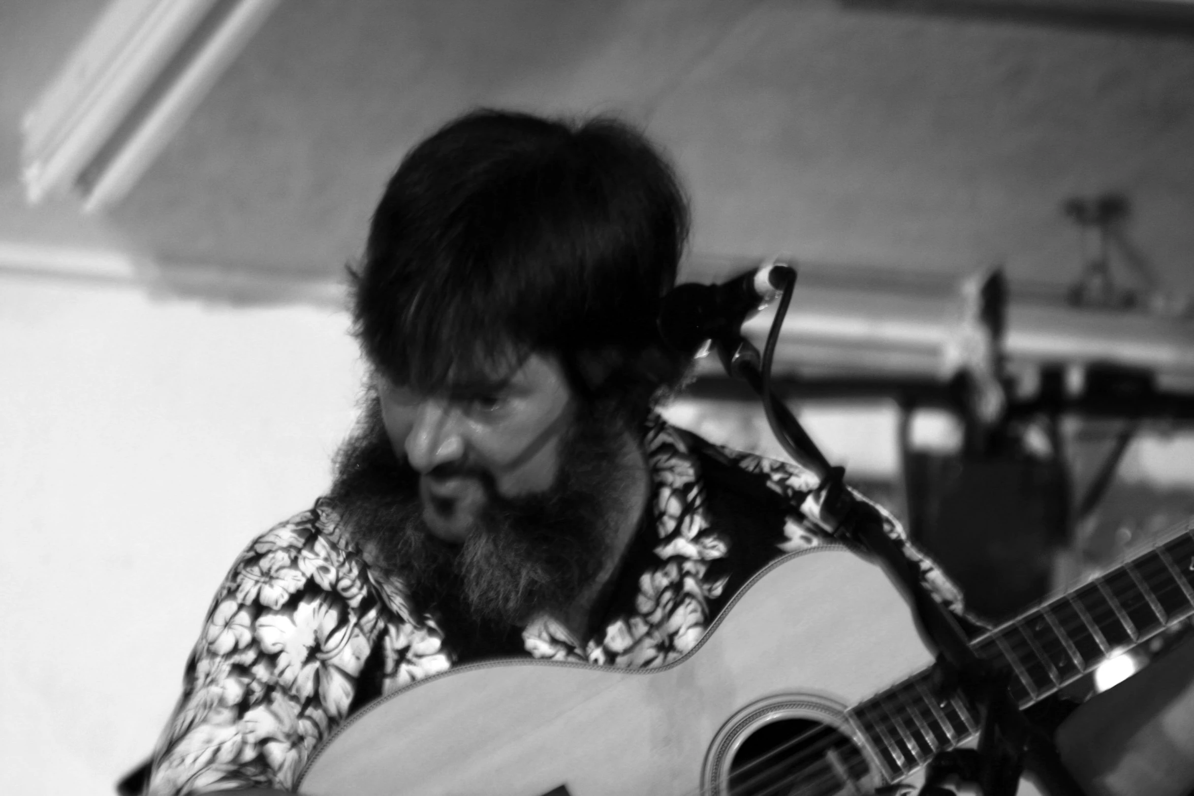 a man in floral shirt playing an acoustic guitar