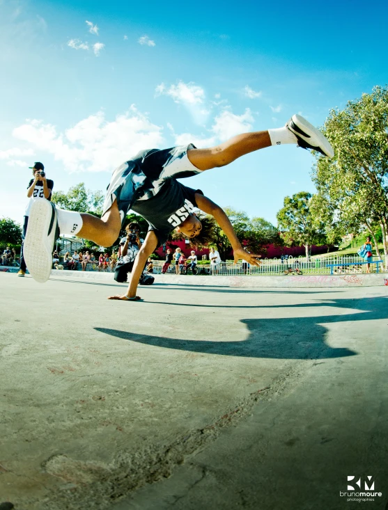 a guy wearing a black and white shirt doing a flip with a skateboard