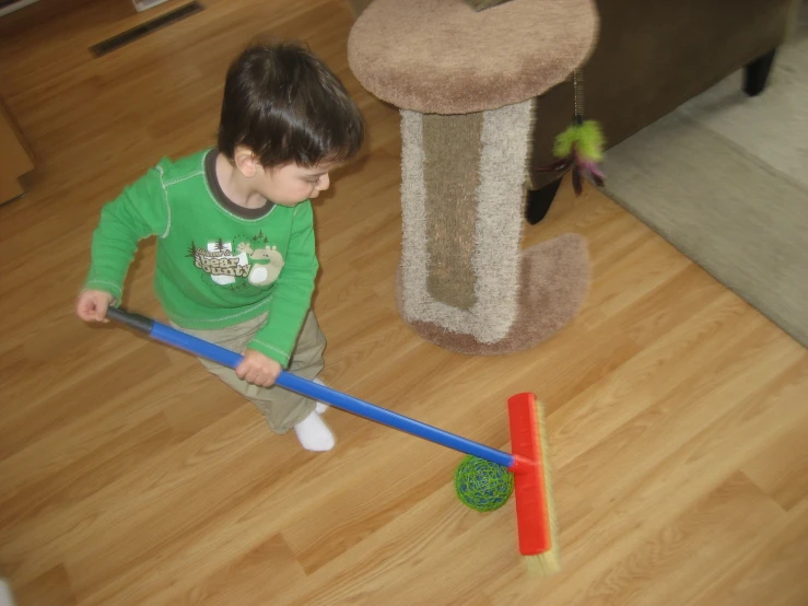 a small child plays with a broom and toy at home