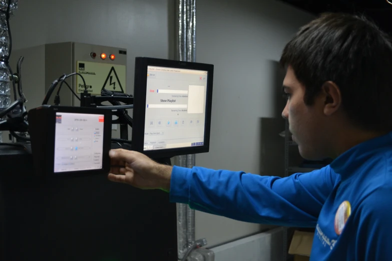 man with blue jacket holding a tablet over a machine