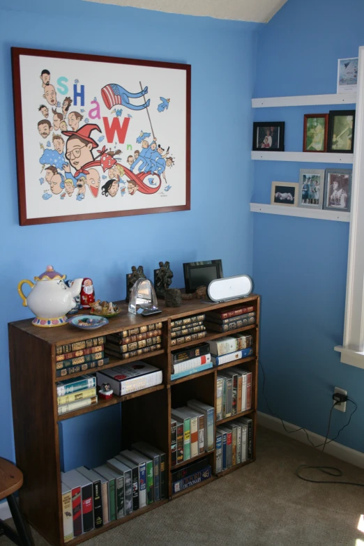 a bookcase with some books on top in front of blue walls