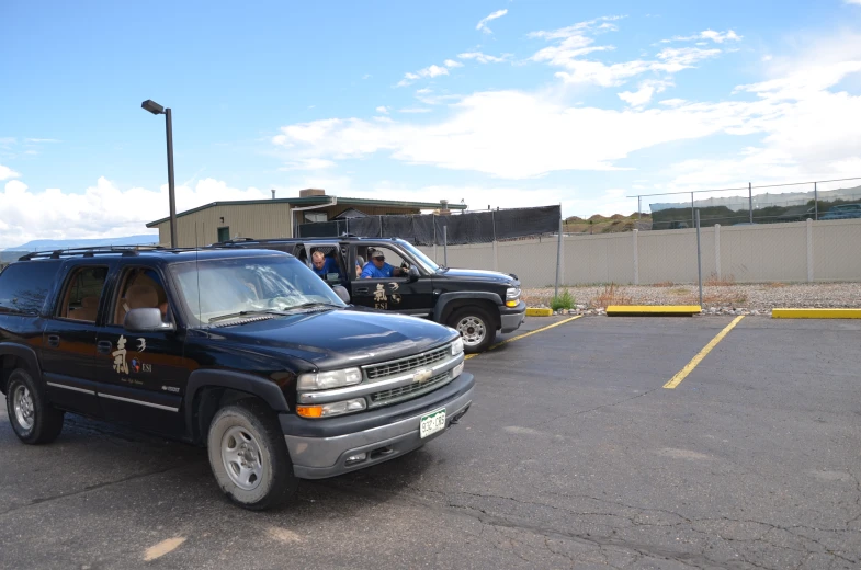 two trucks parked in a parking lot with people in the back