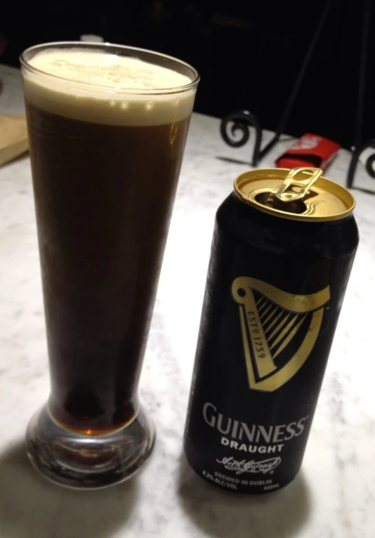 a glass of beer and a beer can sit on a counter