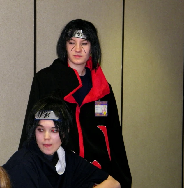 two people with black hair and red scarves standing near one another