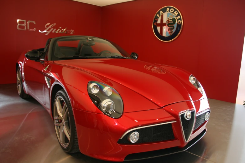 a red sports car on display in front of a wall