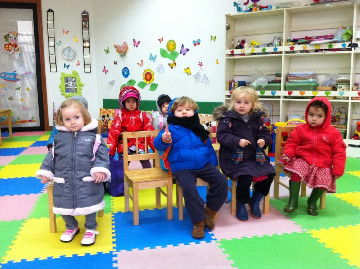 several children sitting and standing around a small table