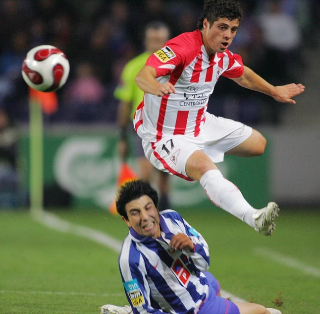 two soccer players playing soccer while spectators watch