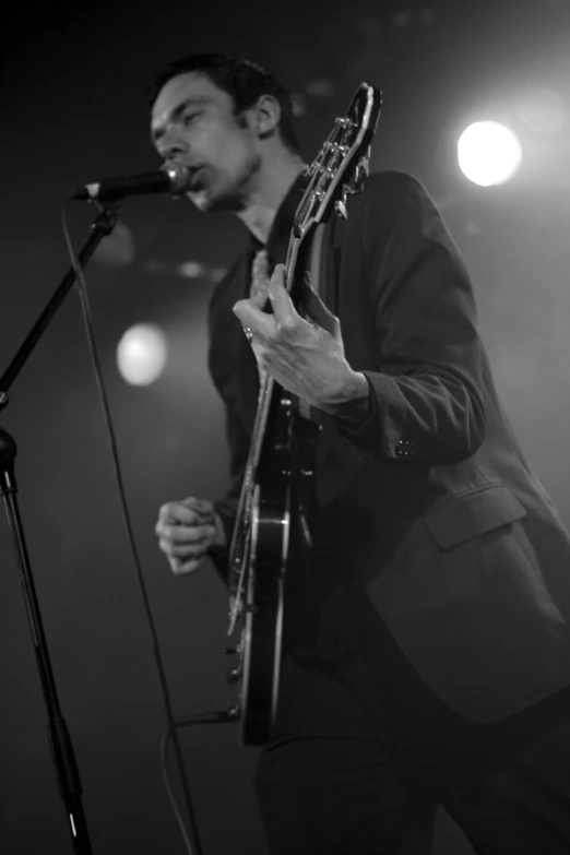 a man in a suit is playing his guitar