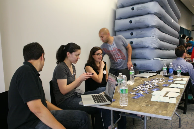 people sitting around a table with some paper and plastic bags on it