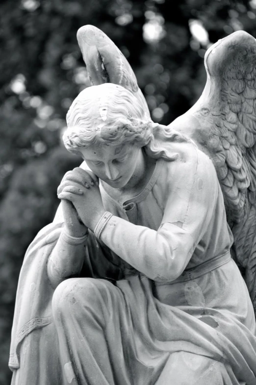 an angel kneeling with his hands together and praying