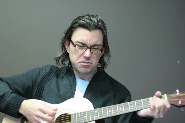a man wearing glasses playing a guitar