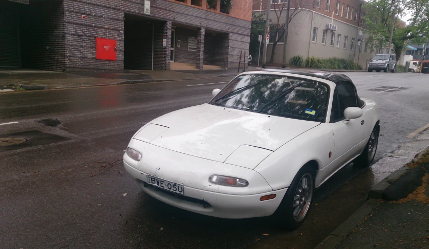 a white sports car is parked on the side of the road