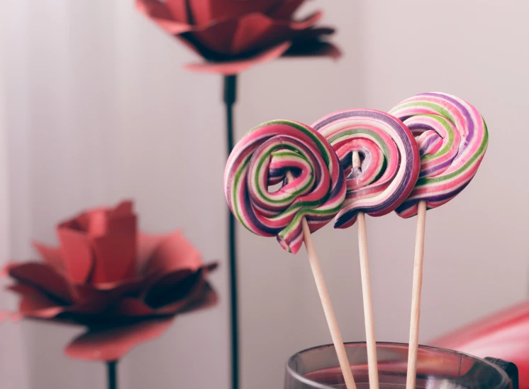 some candy lollipops in a cup sitting on a table