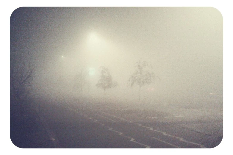 a foggy street with no cars and a person walking down the road