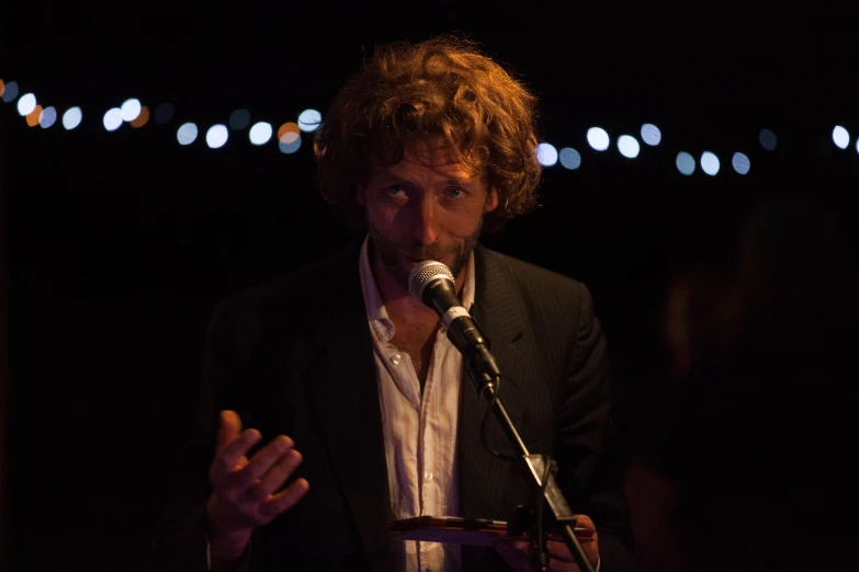 a man speaking into a microphone while standing