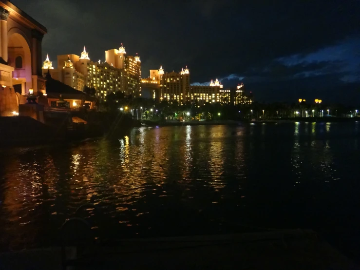 a lit up city is shown next to the water