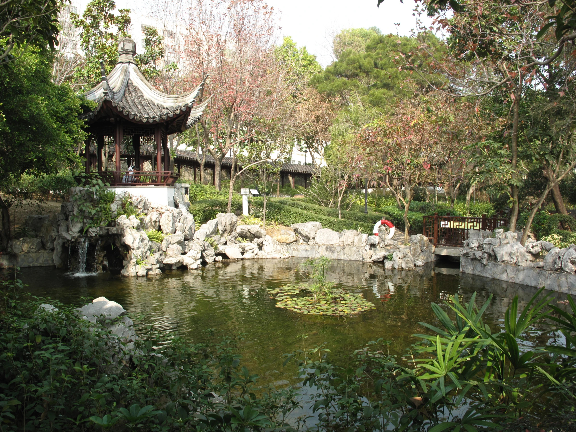 a pond with water surrounded by trees and a gazebo