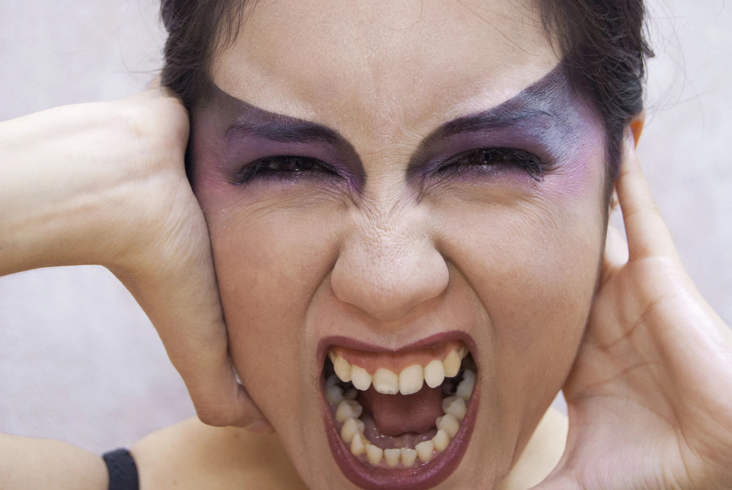 a woman with black and purple make - up on her face has an open mouth