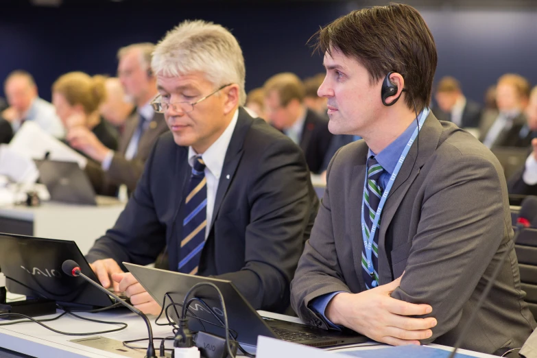 two men in suit sitting at a meeting