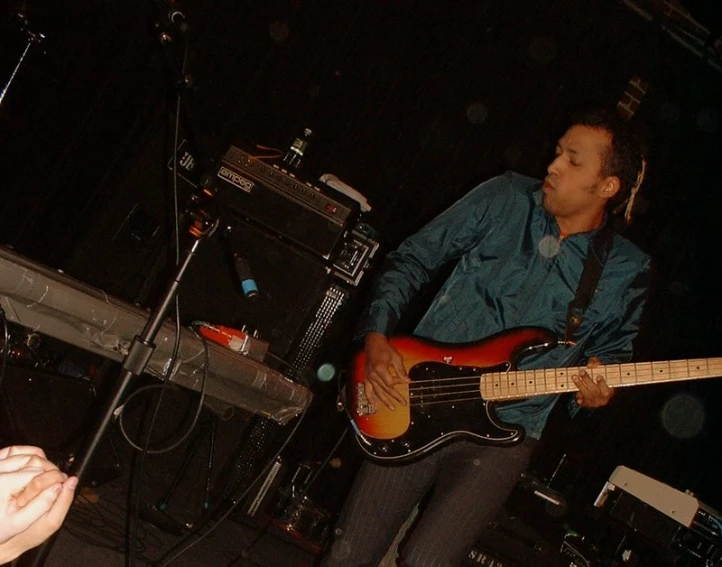 a man in blue shirt holding an orange guitar on stage